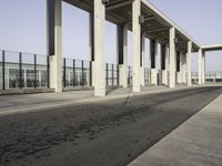 an empty sidewalk that has some columns in it under a blue sky with clouds on the top