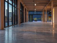 large open space with windows, floor to ceiling glass, and tiled concrete floors along the side of each room