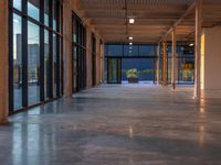 large open space with windows, floor to ceiling glass, and tiled concrete floors along the side of each room