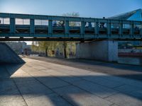 a skateboarder riding on a cement ramp next to a city street under a bridge