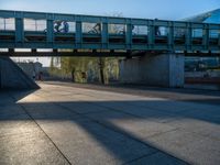 a skateboarder riding on a cement ramp next to a city street under a bridge