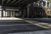 a street corner with a car parked under a bridge as if to get under the tracks