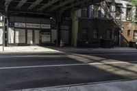 a street corner with a car parked under a bridge as if to get under the tracks