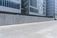 two people are walking across an empty concrete walkway near the water way in city buildings