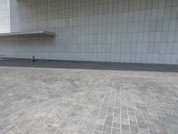 a red fire hydrant sitting on top of a stone floor in front of a white building