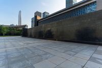 a paved area has a circular logo drawn on it with a skyscraper in the background