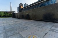 a paved area has a circular logo drawn on it with a skyscraper in the background