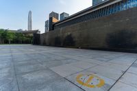 a paved area has a circular logo drawn on it with a skyscraper in the background