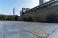 a paved area has a circular logo drawn on it with a skyscraper in the background