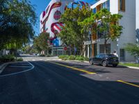 cars are parked in a parking lot in front of a building with a giant american flag