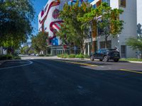 cars are parked in a parking lot in front of a building with a giant american flag