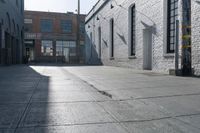 a skateboard is parked at the side of a building's entrance, while people ride on the sidewalk nearby