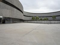 a building with cement roof near green grass and lawn in front of it, under a gray sky