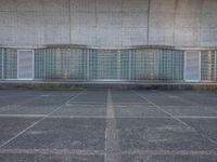 two empty parking spaces with two empty doors and a large window on the wall between two buildings