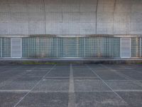 two empty parking spaces with two empty doors and a large window on the wall between two buildings