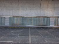 two empty parking spaces with two empty doors and a large window on the wall between two buildings