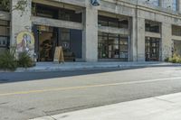 a city street is empty in front of a building with graffiti on the side of the street