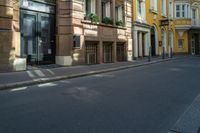 a number of building's in an alley with yellow walls and black doors and window sills