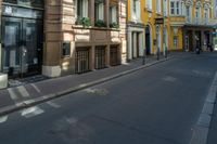 a number of building's in an alley with yellow walls and black doors and window sills