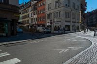 a busy intersection with cars, buildings and bicycles on the street while pedestrians walk across it