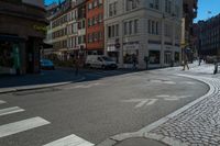 a busy intersection with cars, buildings and bicycles on the street while pedestrians walk across it