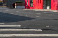 a man on a red motorcycle riding down the street on a crosswalk with buildings in the background