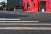 a man on a red motorcycle riding down the street on a crosswalk with buildings in the background