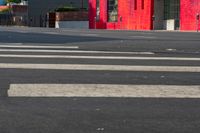 a man on a red motorcycle riding down the street on a crosswalk with buildings in the background