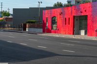 a man on a red motorcycle riding down the street on a crosswalk with buildings in the background