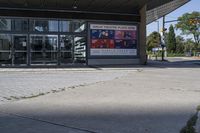 a person sitting at the bench in front of a mall that is empty of people