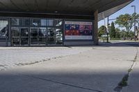 a person sitting at the bench in front of a mall that is empty of people