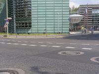 the man is standing on the street corner near some buildings on his cell phone, and holding a cell phone in his right hand