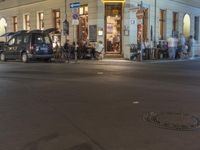 a manhole is seen at the middle of the city intersection at night, with people lined up along it