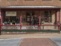 antique items displayed at the front porch of a store on a brick building with pillars