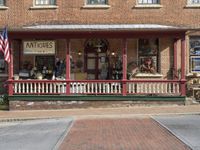 antique items displayed at the front porch of a store on a brick building with pillars