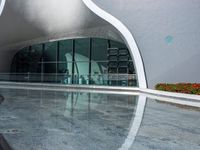 an empty modern building with a reflection in the pool water surrounding it's patio