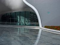 an empty modern building with a reflection in the pool water surrounding it's patio