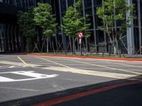 a red stop sign sitting next to some trees and bushes in a parking lot surrounded by tall buildings