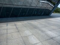 a stone floor next to a building near water pipes and a sidewalk with people on it