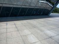 a stone floor next to a building near water pipes and a sidewalk with people on it