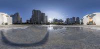 a large object that is sitting in the middle of a puddle of water with buildings behind it