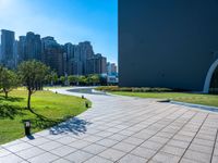 an empty park in front of a city with tall buildings and many trees in the middle