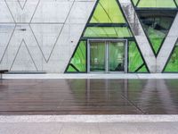 a bench and a wall with geometric glass panels in front of it with someone on a sidewalk walking by it