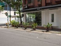 a street corner with plants and buildings in the background under an overhanged awning