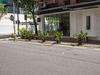 a street corner with plants and buildings in the background under an overhanged awning