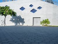 the side of a large building has windows with rounded shapes and trees on either side