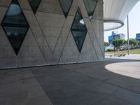 the skateboarder is practicing his moves in front of a building with geometric windows