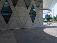 the skateboarder is practicing his moves in front of a building with geometric windows