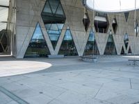 the skateboarder is practicing his moves in front of a building with geometric windows