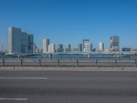 the highway and bridge leading to a city in japan and has tall buildings and blue skies